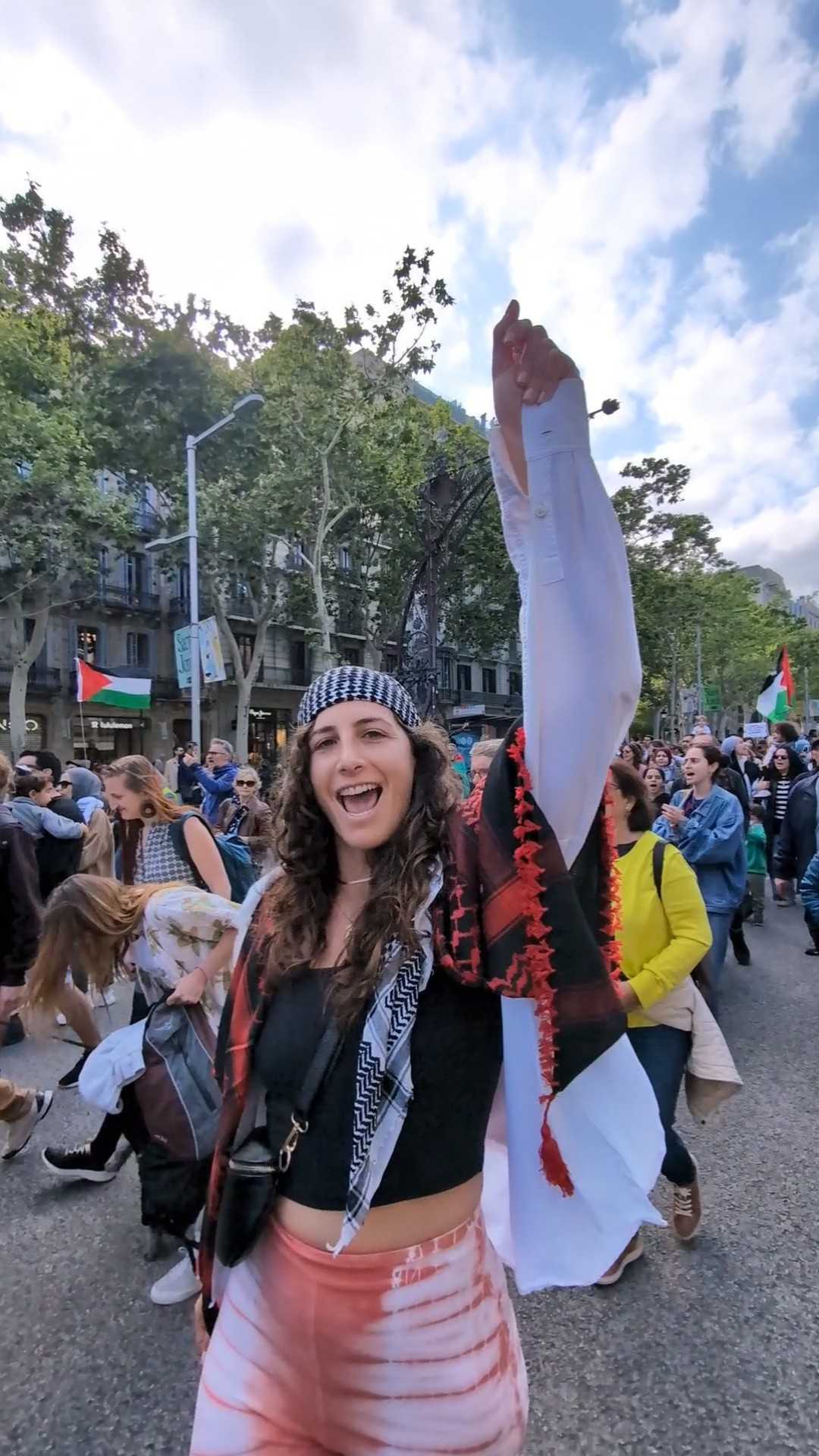 Cloosi founder at a solidarity rally, wearing a keffiyeh and raising her fist in the air